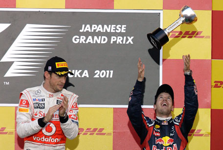 Red Bull driver Sebastian Vettel of Germany tosses his trophy into the air after finishing third in the Japanese Grand Prix to clinch the Formula One drivers championship, at the Suzuka Circuit in Japan on Sunday. McLaren driver Jenson Button of Britain won the race. (AP)
