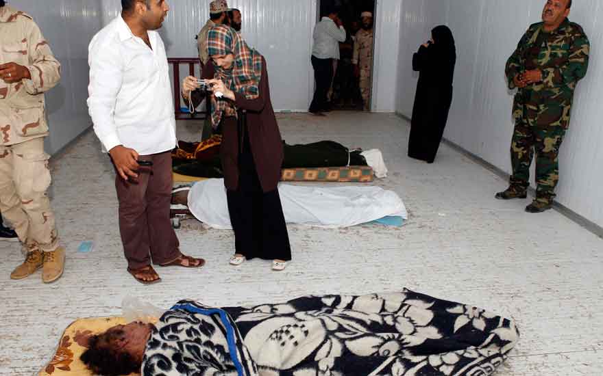 People take pictures of Gaddafi's body inside a meat locker in Misrata (REUTERS)