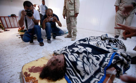 People take pictures of the body of former Libyan leader Muammar Gaddafi inside a meat locker in Misrata October 22, 2011. Gaddafi's body, bloodied and half-naked on a filthy mattress in a meat locker, is the latest spoil of war hauled back to Misrata by its exuberant fighters, confident they are Libya's fiercest revolutionaries. (REUTERS)