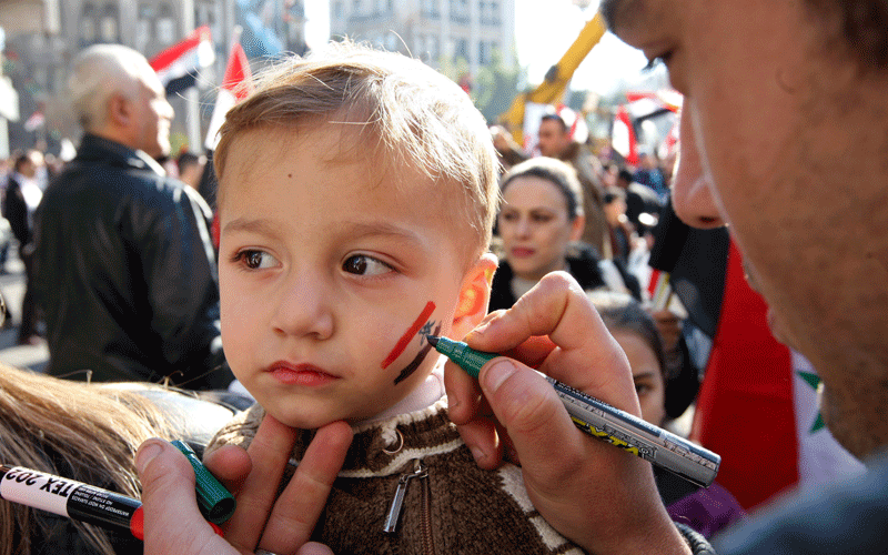 A pro-regime supporter draws the Syrian flag on a child's face during a pro-regime rally in Damascus. Europe and the United States tightened economic sanctions on Syria, ramping up international pressure as the UN said more than 4,000 people had died in a crackdown on dissidents. (AFP)
