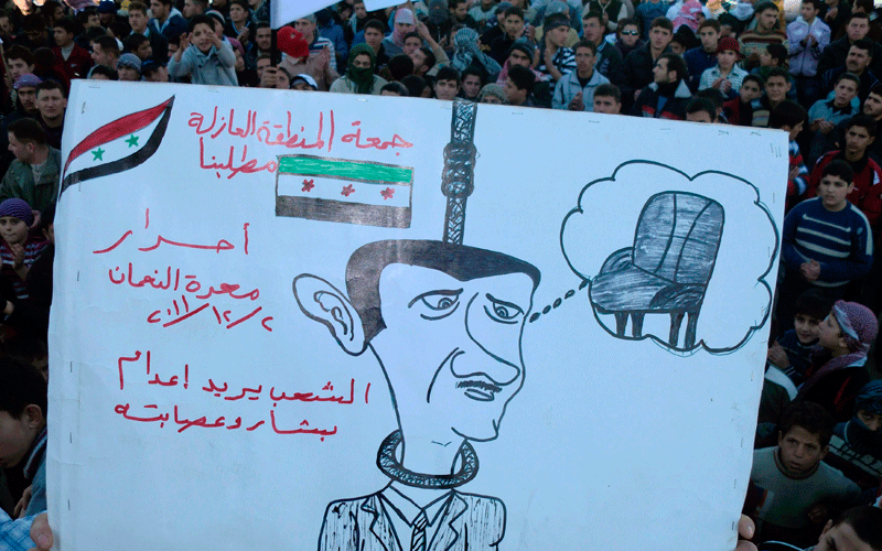 A demonstrator protesting against Syria's President Bashar Al Assad holds a sign during a march through the streets in Marat al Numan near Adlb. The banner reads, "People want the execution of Bashar and his gang". (REUTERS)