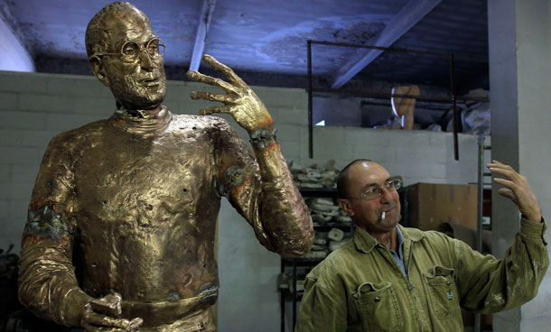An assistant to Hungarian sculptor Erno Toth mimics the pose of the sculptor's latest work, a bronze statue of late Apple co-founder Steve Jobs, in Budapest December 6, 2011. The statue was commissioned by chief of Hungarian software maker Graphisoft Gabor Bojar and will be delivered on December 20.  (REUTERS)