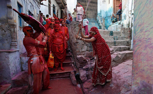 A man shields himself from a woman playfully beating him with a bamboo stick during "Lathmar Holi" at Barsana in the northern Indian state of UP. In a Holi tradition unique to Barsana, men sing provocative songs to gain the attention of women, who then "beat" them with bamboo sticks called "lathis".(REUTERS)