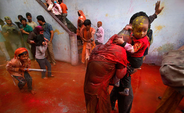 A boy sprays coloured water on a family during the "Lathmar Holi" at the village of Nandgaon in Uttar Pradesh. In a Holi tradition unique to Nandgaon and Barsana villages, men sing provocative songs to gain the attention of women who then "beat" them with bamboo sticks called "lathis". (REUTERS)