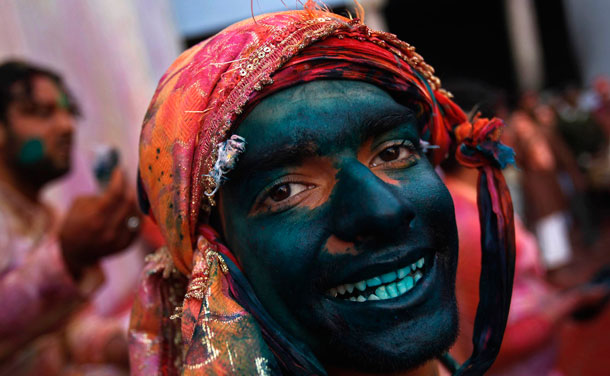 A man daubed in coloured powder smiles as he celebrates "Lathmar Holi" at village Nandgaon in Uttar Pradesh. In a Holi tradition unique to Nandgaon and Barsana villages, men sing provocative songs to gain the attention of women, who then "beat" them with bamboo sticks called "lathis".  (REUTERS)