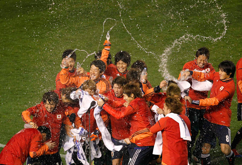 Japan's players splash water on their head coach Takashi Sekizuka (bottom left) after defeating Bahrain at their Asian qualifying soccer match for the 2012 London Olympics Games in Tokyo on March 14. (Reuters)