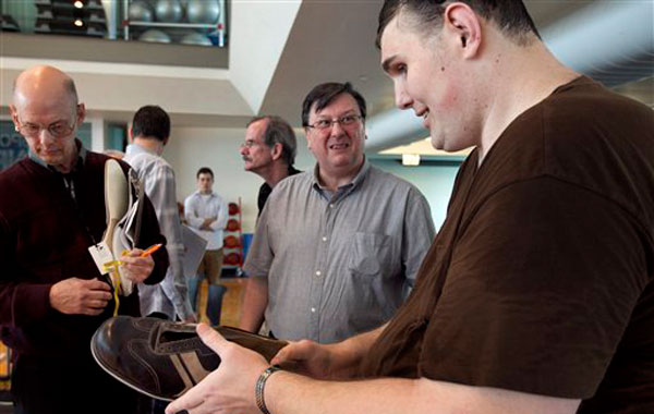 Igor Vovkovinskiy, of Rochester, Minn., currently the tallest man in the United States at seven feet eight inches, right, speaks with Trevor Kirby, center, a shoe engineer, at Reebok headquarters, in Canton, Mass., Thursday, May 3, 2012. Vovkovinskiy, who has a shoe size between 22 and 26, says he's had 16 surgeries in six years to fix problems created by shoes that didn't fit. Reebok is providing a pair of sneakers to Vovkovinskiy at no charge (AP)