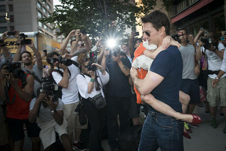 Actor Tom Cruise carries his daughter Suri past a group of photographers as they make their way from a hotel in New York. (REUTERS)