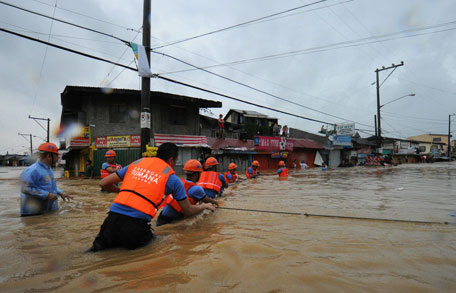 Rescuers cross flood waters to help evacuate residents from their homes in the village of Tumana, Marikina town, in suburban Manila after torrential rains inundated most of the capital. (AFP)