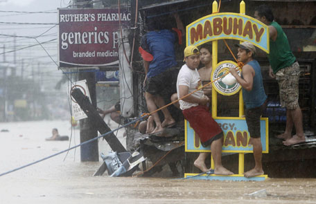 Residents climb onto higher ground near a flooded village in Marikina City, Metro Manila. (REUTERS)