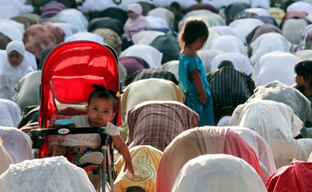 A baby girl sits in her pram while her mother prays to mark the Muslim sacrifice day of Eid al-Adha in Makassar in Indonesia's South Sulawesi province October 26, 2012. Indonesia, the world's most populous Muslim nation, celebrates Eid al-Adha by slaughtering goats and cows and distributing the meat to the poor. (REUTERS)