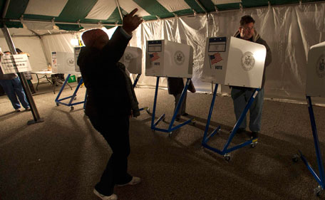 A poll worker directs voters to ballot booths during the U.S. presidential election at a poling station, lit by generator lights, in the Staten Island Borough of New York November 6, 2012. The aftermath of Superstorm Sandy created chaos and long lines at voting stations in the U.S. Northeast on Tuesday while officials braced for a new storm due to batter the region on Wednesday. (REUTERS)