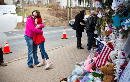 Deborah Gibelli holds her daughter, Alexandra Gibelli, age 9, while looking at a memorial for those killed in the school shooting at Sandy Hook Elementary School, on December 24, 2012 in Newtown, Connecticut. Donations and letters are pouring in from across the country as the town tries to recover from the massacre. (Getty Images/AFP)