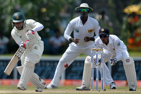 Bangladeshi captain Mushfiqur Rahim (left) is watched by Sri Lankan wicketkeeper Dinesh Chandimal as he plays a shot during the fourth day of the first Test at the Galle International Cricket Stadium in Galle on March 11, 2013. (AFP)