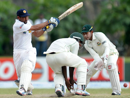 Sri Lankan batsman Tillakaratne Dilshan (left) plays a shot as Bangladeshi wicketkeeper and captain Mushfiqur Rahim (right) reacts during the fourth day of their first Test at the Galle International Cricket Stadium in Galle on March 11, 2013. (AFP)
