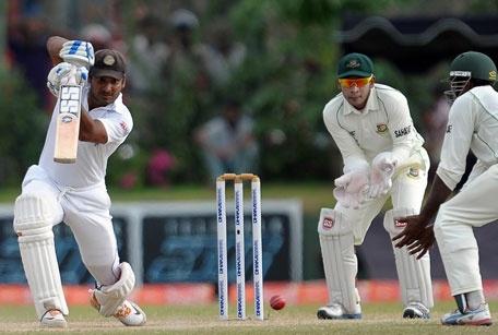 Sri Lankan batsman Kumar Sangakkara (left) plays a shot as Bangladeshi wicketkeeper and captain Mushfiqur Rahim (cnetre) reacts during the fourth day of their first Test at the Galle International Cricket Stadium in Galle on March 11, 2013. (AFP)