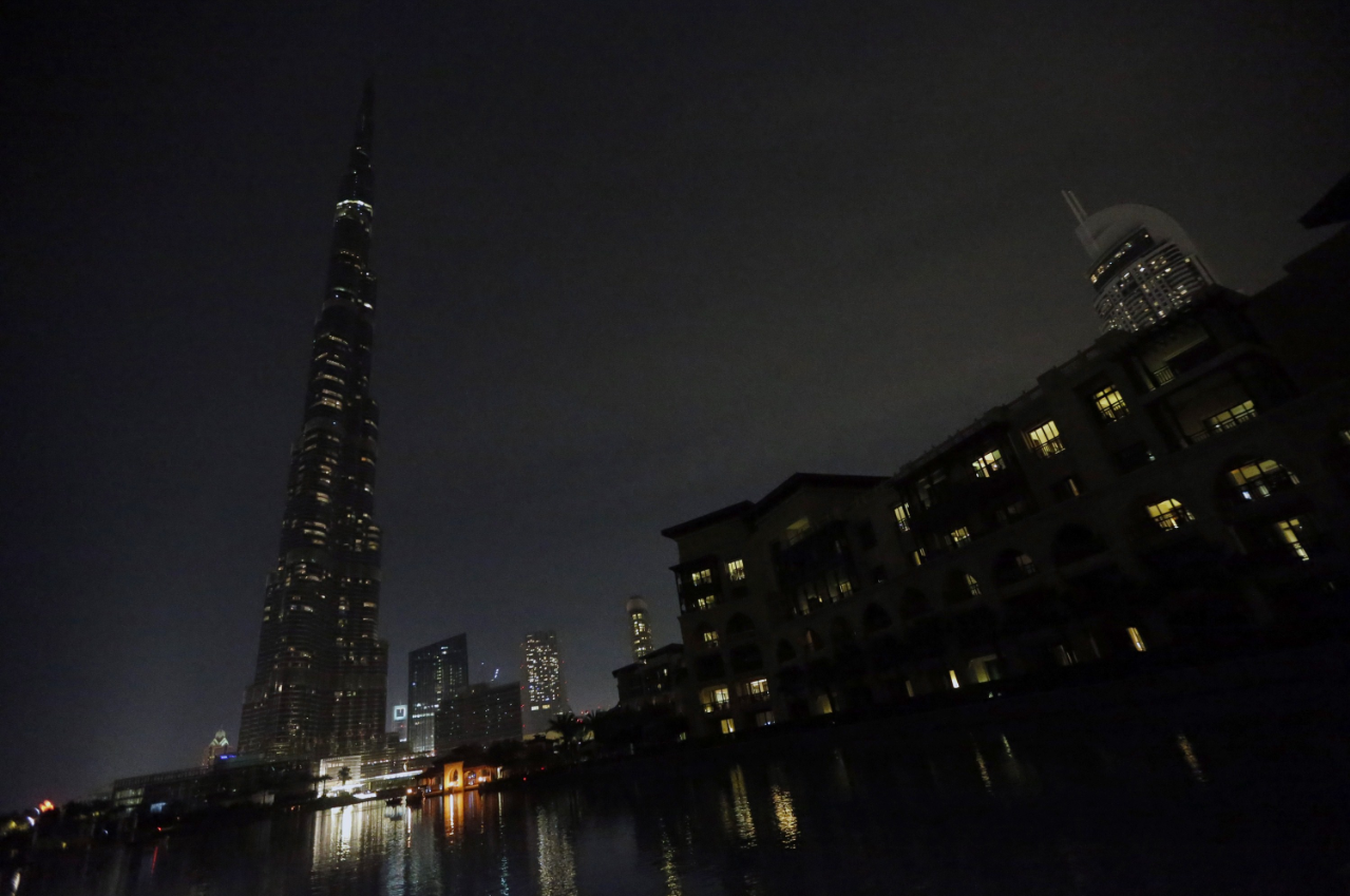 The lights on the Burj Khalifa tower (L) are switched off for an hour in Downtown Dubai, on March 23, 2013, as iconic landmarks and skylines are plunged into darkness as the "Earth Hour" switch-off of lights around the world got under way to raise awareness of climate change.  (AFP)