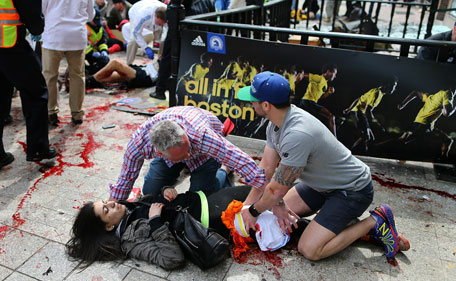 An injured woman is tended to at the finish line of the Boston Marathon,  in Boston, Monday, April 15, 2013. Two explosions shattered the euphoria of the Boston Marathon finish line on Monday, sending authorities out on the course to carry off the injured while the stragglers were rerouted away from the smoking site of the blasts. (AP)