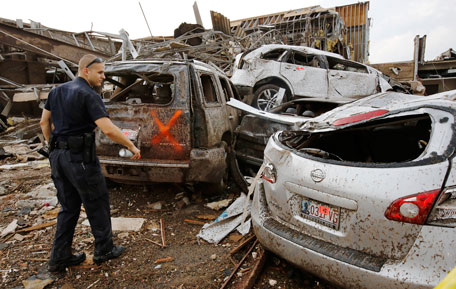 A security officer marks vehicles with spray paint after checking for victims and determining no one is inside, at a business complex west of Interstate 35, south of 4th Street in Moore, Okla., on Monday, May 20, 2013. (AP)
