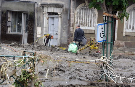 A man walks on a mud covered street in Saint-Beat after their village was submerged by flash floods on June 19, 2013.  Flash floods in southwestern France claimed two elderly victims in the space of 24 hours and forced the inundated grotto at Lourdes to remain closed for a second day, officials said. (AFP)