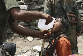 In this Friday, June 21, 2013 photo, an Indian army soldier helps a young girl, affected by floods, drink water before evacuating her from the upper reaches of mountains, in Gaurikund, in northern Indian state of Uttrakhand. Officials say soldiers are working to evacuate tens of thousands of people still stranded in northern India where nearly 600 people have been killed in monsoon flooding and landslides. (AP Photo)