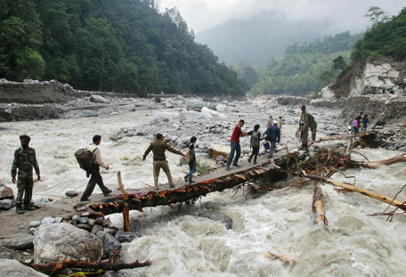 Indian army personnel help stranded people cross a flooded river after heavy rains in the Himalayan state of Uttarakhand June 23, 2013. Flash floods and landslides unleashed by early monsoon rains have killed at least 560 people in Uttarakhand and left tens of thousands missing, officials said on Saturday, with the death toll expected to rise significantly. Picture taken June 23, 2013. (REUTERS)