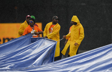 Groundsmen pull a plastic sheet to cover the field as rain interrupts the fifth match of the Tri-series between Sri Lanka and West Indies at the Queen's Park Oval in Port of Spain on July 7, 2013. (AFP)