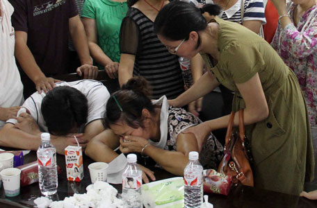 The parents (bottom) of Wang Linjia, one of the two girls killed during the Asiana Airlines plane crash on Saturday, cry at a middle school in Quzhou, Zhejiang province, July 7, 2013. An emergency vehicle rushing to the scene of the Asiana Airlines crash at San Francisco's international airport may have run over one of the two teenage Chinese girls killed in the incident, the local fire department said on Sunday. Picture taken July 7, 2013. (REUTERS)