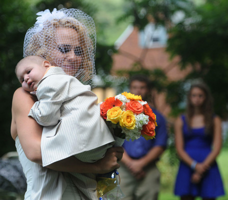 Christine Swidorsky carries her son and the couple's best man, Logan Stevenson, 2, down the aisle to her husband-to-be Sean Stevenson during the wedding ceremony. (AP)