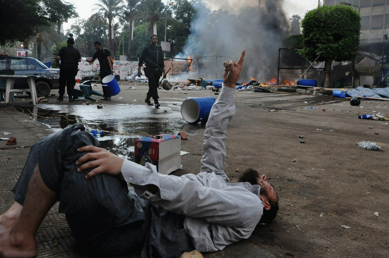 A man lies on the ground as Egyptian security forces clear a sit-in camp set up by supporters of ousted President Mohammed Morsi near Cairo University in Cairo's Giza district on Wednesday. (AP)