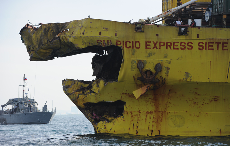 A Philippine Navy boat (L) guards a cargo ship with its bow destroyed on August 17, 2013 after it collided with the ferry St. Thomas Aquinas the night before off the town of Talisay near the Philippines' second largest city of Cebu. Philippine rescuers searched on August 17 for more than 200 people missing after the ferry collided with the cargo ship in thick darkness and sank almost instantly, with 26 already confirmed dead. (AFP)