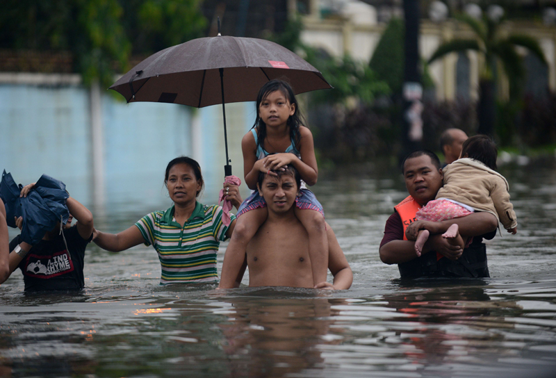 Residents walk through a flooded street in Manila on August 20, 2013. Flood-battered residents of the Philippine capital fled their homes or sat on rooftops on August 20 as relentless monsoon rains, which have killed seven people, submerged more than half of Manila. (AFP)