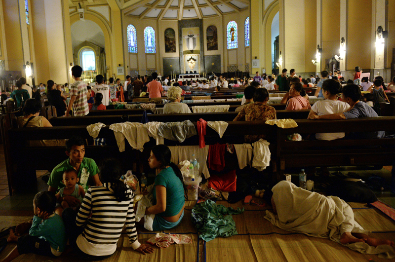 Residents affected by floods rest inside a church used as a temporary evacuation centre as heavy rains continued in Manila on August 20, 2013. Flood-battered residents of the Philippine capital and surrounding areas appealed for help August 20 as relentless monsoon rains, which have claimed at least seven lives, submerged more than half of Manila.  (AFP)