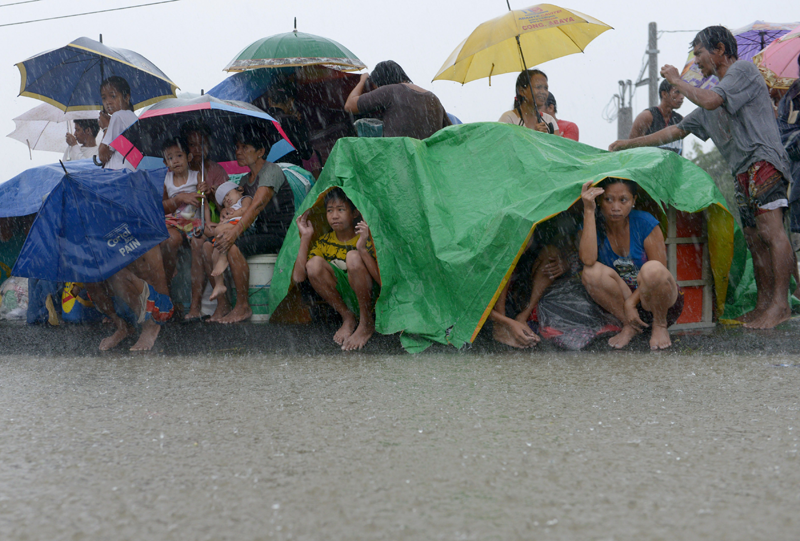 TOPSHOTSResidents take shelter from the rain after floodwaters inundated their homes in the farming town of Novaleta, some 26 kilometres outside Manila on August 19, 2013. Torrential rain paralysed large parts of the Philippine capital on August 19 as neck-deep water swept through homes, while floods in northern farming areas claimed at least one life. (AFP)