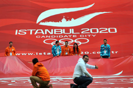 Picture taken on March 24, 2013 shows people holding a poster promoting Istanbul's candidacy to host the 2020 Games during a visit of the International Olympic Committee's evaluation commission and of the Turkish National Olympic Committee at the Telekom Arena Stadium in Istanbul on March 24, 2013. (AFP)