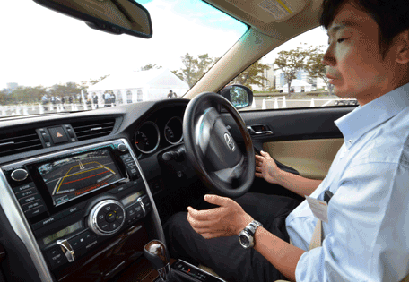 This photo taken on October 10, 2013 shows a Japanese auto giant Toyota Motor employee demonstrating the advanced driving support system "Automated Highway Driving Assist" in Tokyo. The two vehicles communicate each other, keeping their lane and following the preceding vehicle to maintain a safety distance. Cars that drive themselves -- and avoid collisions -- could be on the market within a few years as the world's biggest vehicle maker showed off its latest automated driving technology. (AFP)