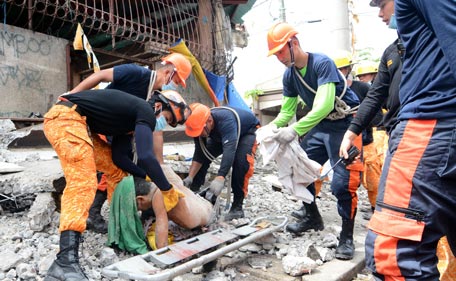 Rescuers pick up the body of a dead man near the port in Cebu City, Philippines after a 7.1 magnitude earthquake struck the region on October 15, 2013.  At least 20 people were killed on October 15 when the earthquake tore down buildings across three islands that are among the Philippines' most popular tourist attractions, authorities said. (AFP)