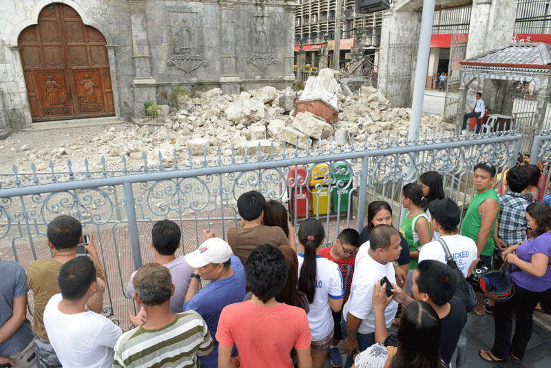 People look at the ruins of Basilica Minore del Santo Nino bell tower following a 7.1-magnitude quake in Cebu on October 15. (AFP)
