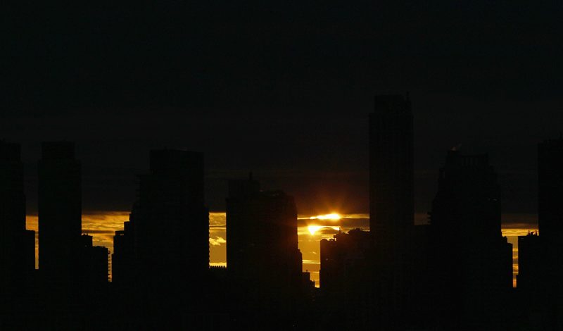 The sun rises behind the skyline of Manhattan as it is partially eclipsed by the moon during a hybrid eclipse over New York on Sunday.  (Reuters)