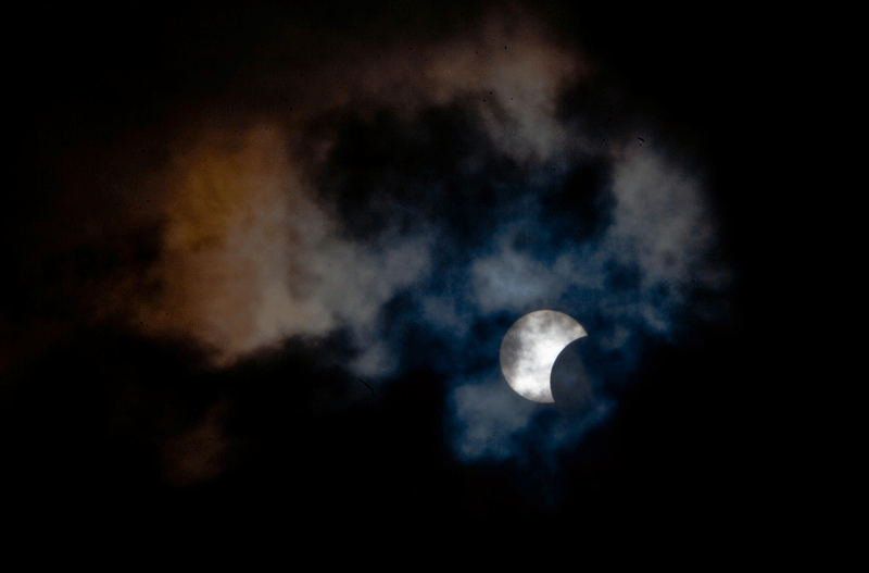 This picture taken on Sunday shows a rare hybrid solar eclipse through clouds from the Canary Island of Tenerife. A rare solar eclipse swept across parts of Africa, Europe and the United States today as the moon blocks the sun either fully or partially, depending on the location. The width of the shadow of the eclipse was 58 km and the maximum duration of totality, the maximum time that the moon covered the sun completely, was 1m 40s, on the Spanish Canary island of Tenerife.  ( AFP)