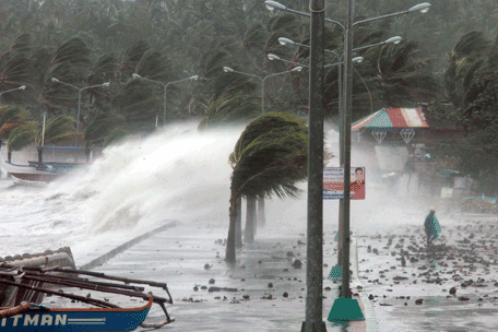 A resident (R) walks past high waves pounding the sea wall amidst strong winds as Typhoon Haiyan hit the city of Legaspi, Albay province, south of Manila on November 8, 2013.  One of the most intense typhoons on record whipped the Philippines on November 8, killing three people and terrifying millions as monster winds tore roofs off buildings and giant waves washed away flimsy homes. (AFP)