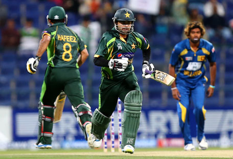 Ahmed Shehzad (centre) of Pakistan and his teammate Mohammad Hafeez run between wickets as bowler Lasith Makinga of Sri Lanka looks on during the 4th One Day International in Abu Dhabi on December 25, 2013. (AFP)