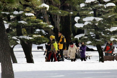 Tourists walk on a snow at a park in Tokyo on February 9, 2014 one day after a heavy snowfall hit the capital.  The heaviest snow in decades to hit the city and other areas of Japan has left at least five dead and 600 injured across the country. (AFP)