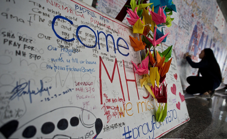 A Malaysian girl writes a message expressing prayers and well-wishes for passengers onboard missing Malaysia Airlines (MAS) flight MH370 at Kuala Lumpur International Airport in Sepang on March 17, 2014. An investigation into the pilots of missing Malaysia Airlines flight 370 intensified on March 17 after officials confirmed that the last words spoken from the cockpit came after a key signalling system was manually disabled. (AFP)
