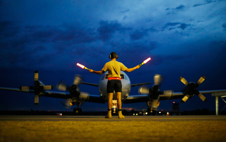 A ground controller guides a Royal Australian Air Force AP-3C Orion to rest after sunset upon its return from a search for Malaysian Airlines flight MH370 over the Indian Ocean, at RAAF Base Pearce north of Perth, March 24, 2014. An Australian navy ship was close to finding possible debris from a missing Malaysia Airlines jetliner on Monday as a mounting number of sightings of floating objects raised hopes wreckage of the plane may soon be found. The HMAS Success should reach two objects spotted by Australian military aircraft by Tuesday morning at the latest, Malaysia's government said, offering the first chance of picking up suspected debris from the plane. (REUTERS)