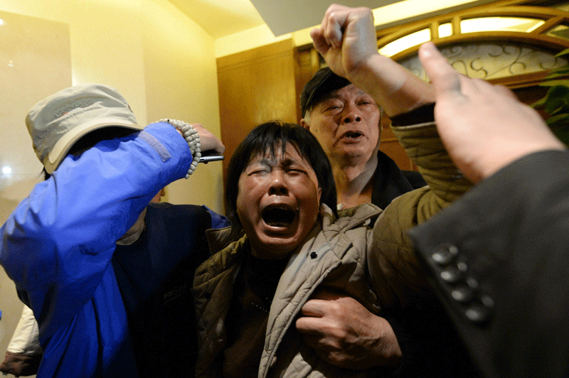 A relative (centre) of passengers on Malaysia Airlines flight MH370 waves her fist as she cries after hearing the news that the plane plunged into Indian Ocean at a hotel in Beijing on March 24.  (AFP)