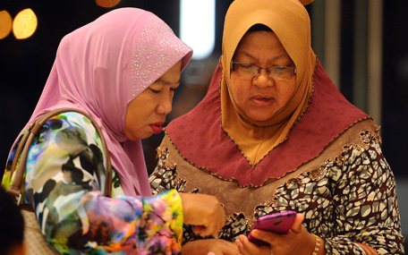 Family members of passengers aboard a missing Malaysia Airlines plane check a mobile phone before a briefing at a hotel in Putrajaya, Malaysia, Tuesday, March 25, 2014. Malaysia said Tuesday that it has narrowed the search for the downed jetliner to an area the size of Texas and Oklahoma in the southern Indian Ocean, while Australia said improved weather would allow the hunt for possible debris from the plane to resume. (AP)