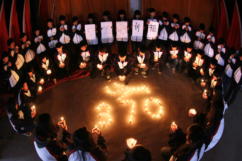High school students hold candles during a vigil for passengers of the missing Malaysia Airline flight MH370 in Lianyungang, east China's Jiangsu province on March 25. Scores of angry relatives of the Chinese passengers aboard Flight MH370 set out on a protest march to the Malaysian embassy in Beijing on March 25 to demand more answers about the crashed plane's fate.  (AFP)