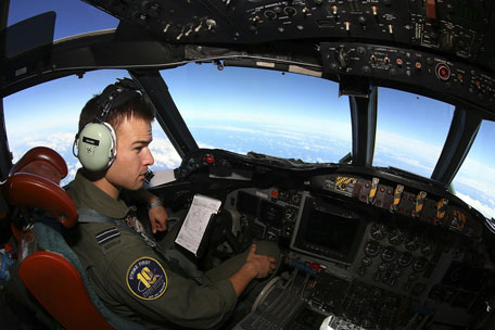In this Wednesday, March 26, 2014 photo, Flight Lt. Russell Adams looks out from the cockpit on board a Royal Australian Air Force AP-3C Orion, during a search for the missing Malaysia Airlines Flight 370 in the southern Indian Ocean. A French satellite scanning the Indian Ocean for remnants of the missing jetliner found a possible plane debris field containing 122 objects, a top Malaysian official said Wednesday, calling it "the most credible lead that we have." (AP)