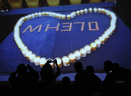 Relatives of passengers aboard Malaysia Airlines MH370 takes picture of a screen while a slideshow is played for the passengers of the missing plane at the Lido Hotel in Beijing March 27, 2014. Severe weather on Thursday halted an air and sea search for a Malaysia Airlines  passenger jet presumed crashed in the southern Indian Ocean, frustrating hopes of finding what new satellite images showed could be a large debris field. (REUTERS)